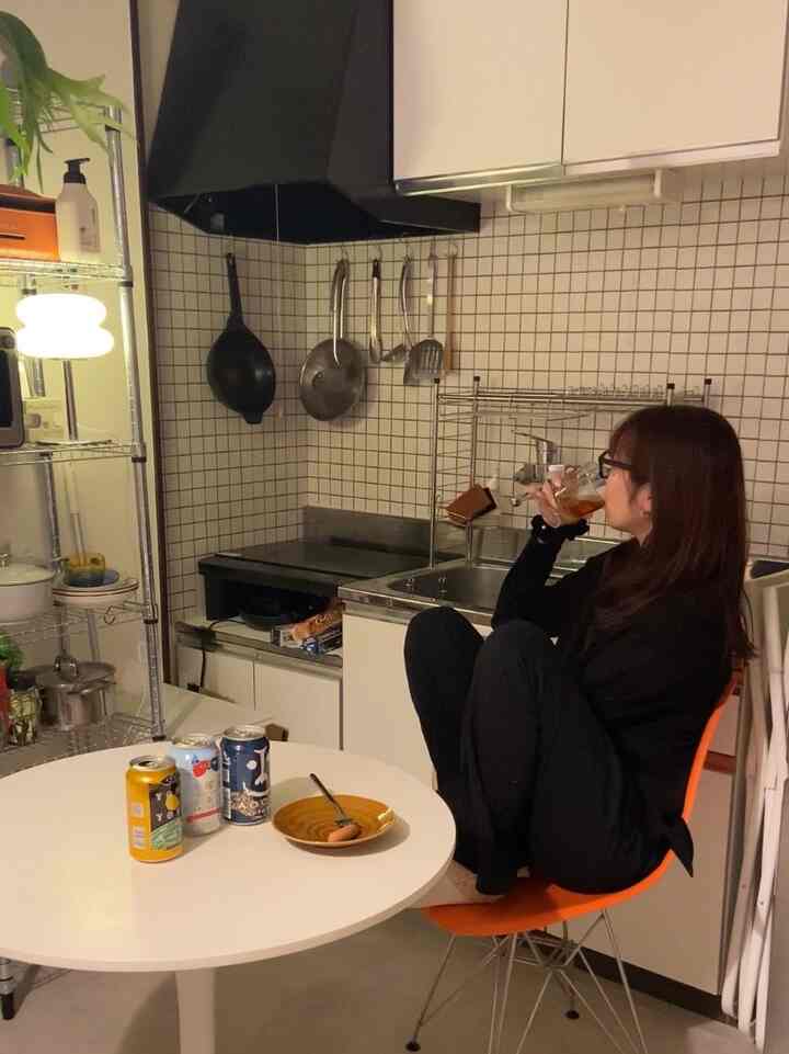 White and black toned 1DK kitchen for a single household, featuring a round dining table and orange chair with cozy atmosphere