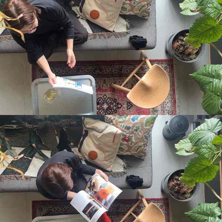 Natural toned studio living room featuring gray sofa, wooden stool, plants, and patterned rugs creating a cozy atmosphere