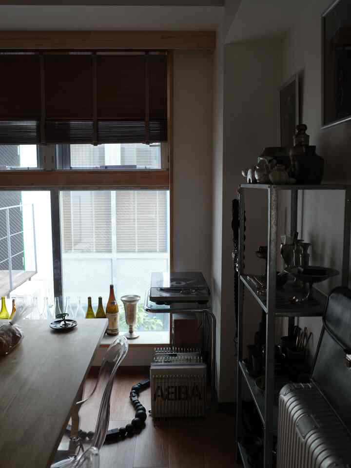 ウッドトーンのナチュラルモダンな1LDKダイニングスペース、ワインボトルと透明なチェアが配置された雰囲気あるホームバー