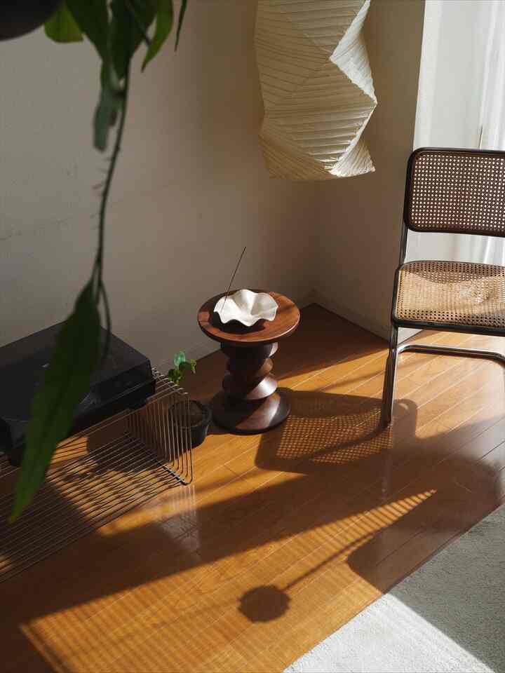 ブラウンの木製床とスツール、白い壁と照明が調和するロフトのリビング空間