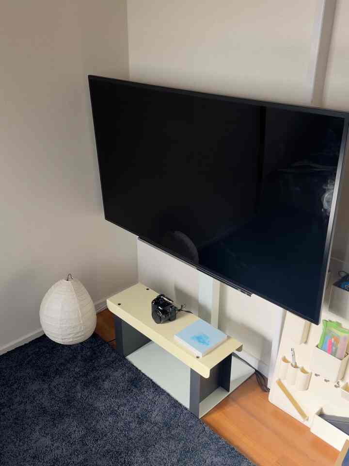 ナチュラルなウッドトーンの床とミニマルなベンチが配置されたコンパクトな一人暮らしのリビング