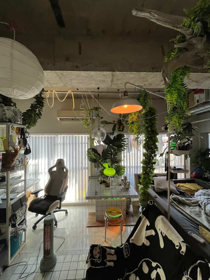 White and green toned studio apartment featuring a gaming chair and table lamp with a natural, cozy atmosphere