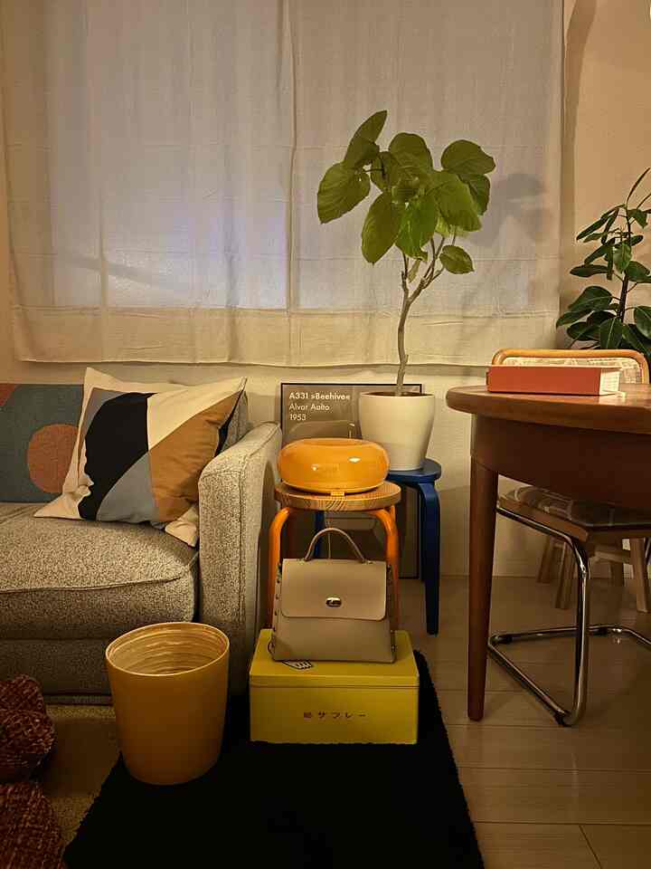 A warm living room with natural wood tones and yellow accents, featuring mid-century modern sofa, dining table, and greenery