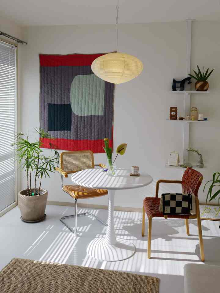 Bright white and natural brown toned dining room with round table, pendant light, and plants creating a cozy space