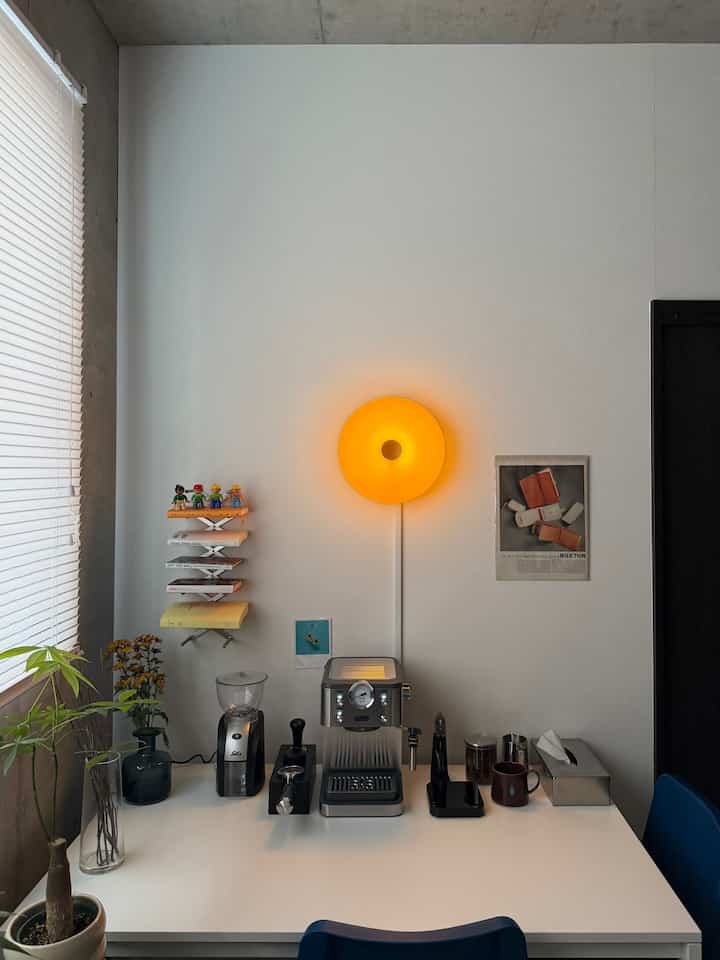 White and silver toned kitchen space featuring a simple dining table with an espresso machine and coffee tools arranged neatly for a clean home cafe interior