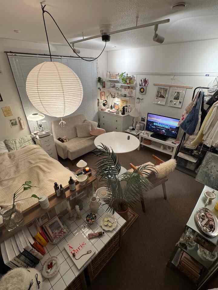 Beige and white toned 7-tatami 1K apartment living room and bedroom with sofa, coffee table, and coffee machine creating cozy atmosphere