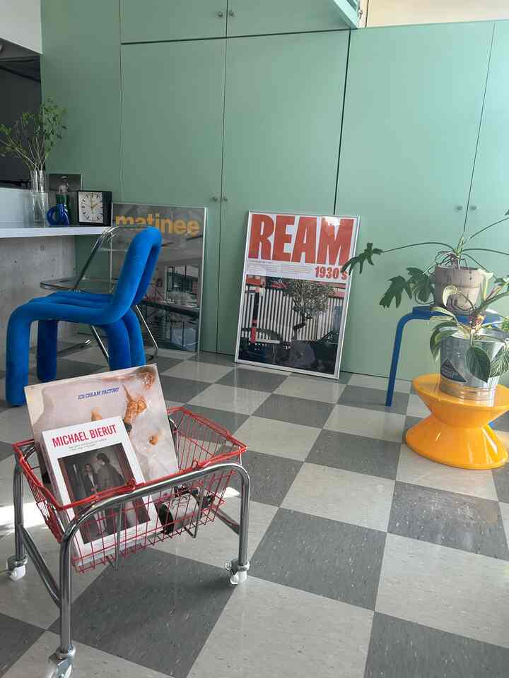 グリーンの壁面と青いベルベットのダイニングチェア、黄色の丸テーブルが調和するミッドセンチュリーモダンのリビング空間