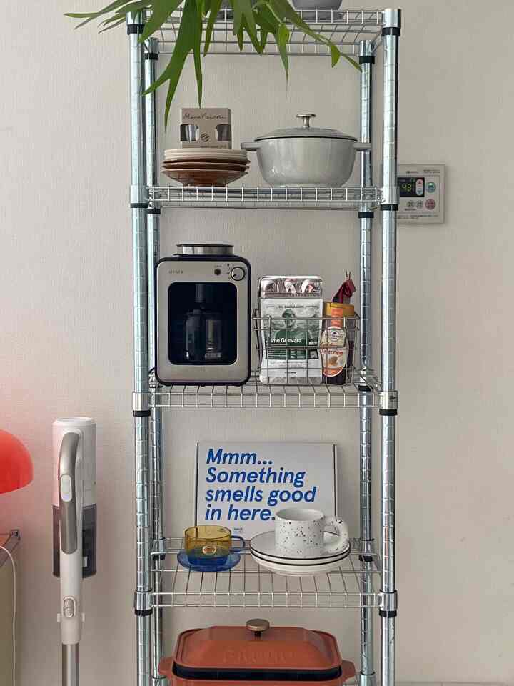 白とグレーのトーンの1DK空間、メタルシェルフにコーヒーマシンと食器が整然と配置されたミッドセンチュリーモダンで雰囲気のあるホームカフェ風インテリア