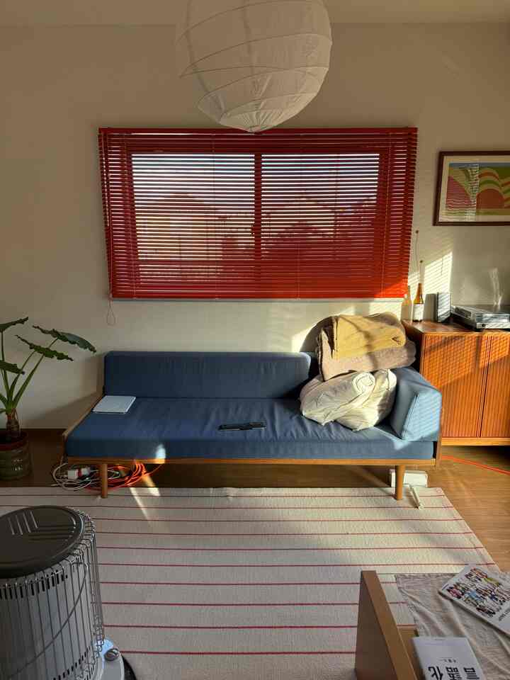 Natural brown and blue toned living room featuring a sofa and red blinds with a modern atmosphere