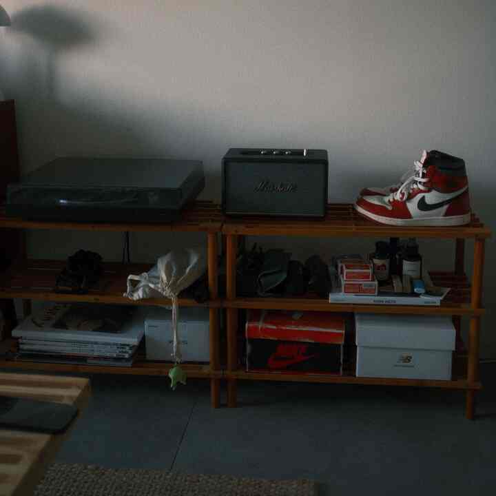 A Nordic-style, clean single household space featuring wood-tone shelving with a turntable, Marshall speaker, and Nike basketball shoes arranged neatly
