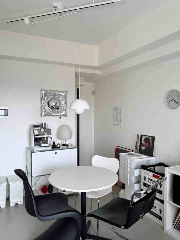 White and black toned dining room featuring a round dining table, multiple chairs, and a modern espresso machine on a storage cabinet