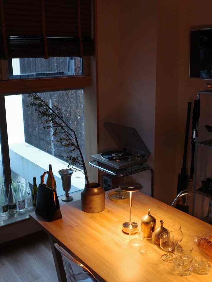 暖かみのあるブラウンの木目調ダイニング、中央にテーブルランプとターンテーブルが配置された雰囲気のある空間