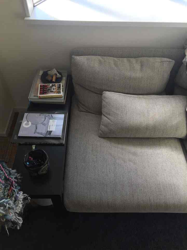 Beige modern living room sofa with a black side table arranged in a cozy space