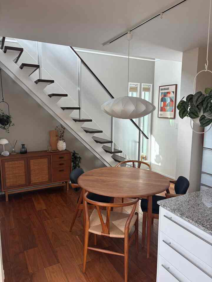 温かみのある木目調と白を基調としたダイニング、丸いダイニングテーブルと椅子が配置された自然な雰囲気のインテリア