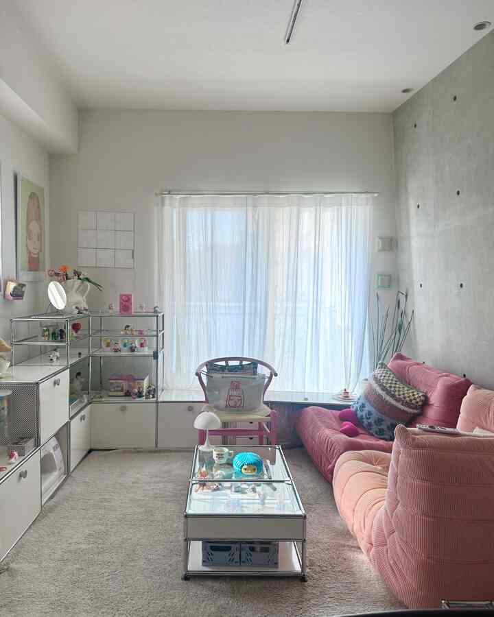 White and pink toned living room featuring large storage units and comfortable sofa in a modern setting