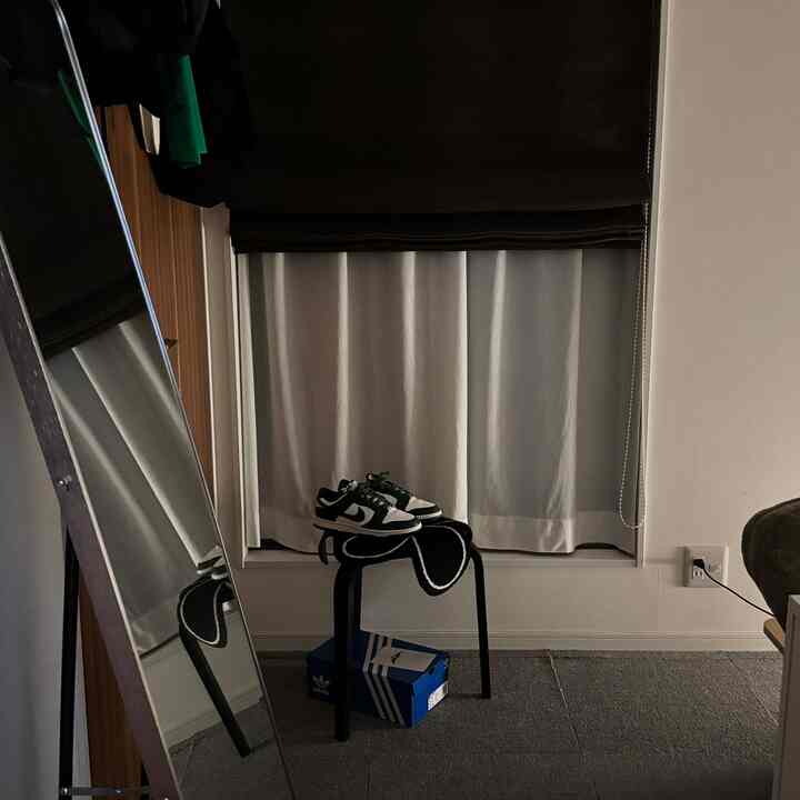 黒と白のトーンのリビング、鏡とスツールに置かれた靴があるシンプルで居心地の良い空間