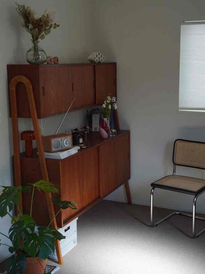 Beige-toned studio living space featuring wood tone storage cabinets and rattan chair creating a natural atmosphere