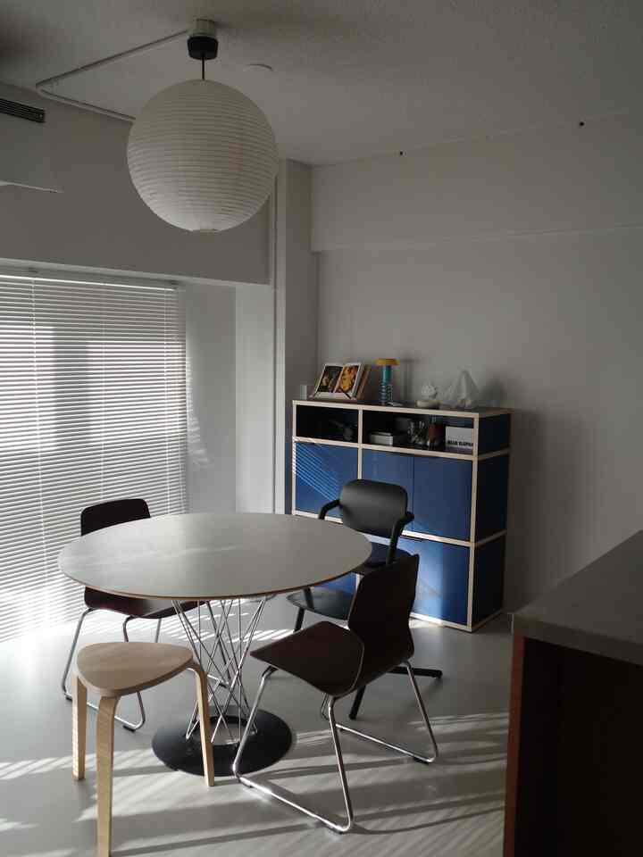 ホワイトとスカイブルーの色調のダイニング、丸テーブルと様々な椅子が配置されたモダンな雰囲気のインテリア