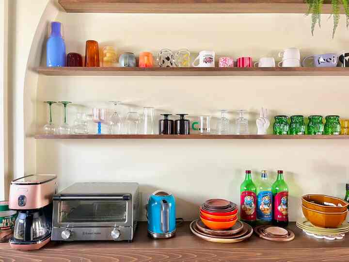 Natural tone kitchen featuring colorful glasses and neatly arranged kitchen appliances with a cozy atmosphere