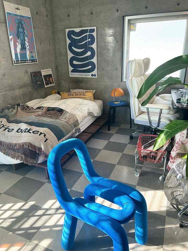 ホワイトとブルーの色調の寝室、ミッドセンチュリーモダンの椅子とデスクが配置された印象的なワンルームインテリア