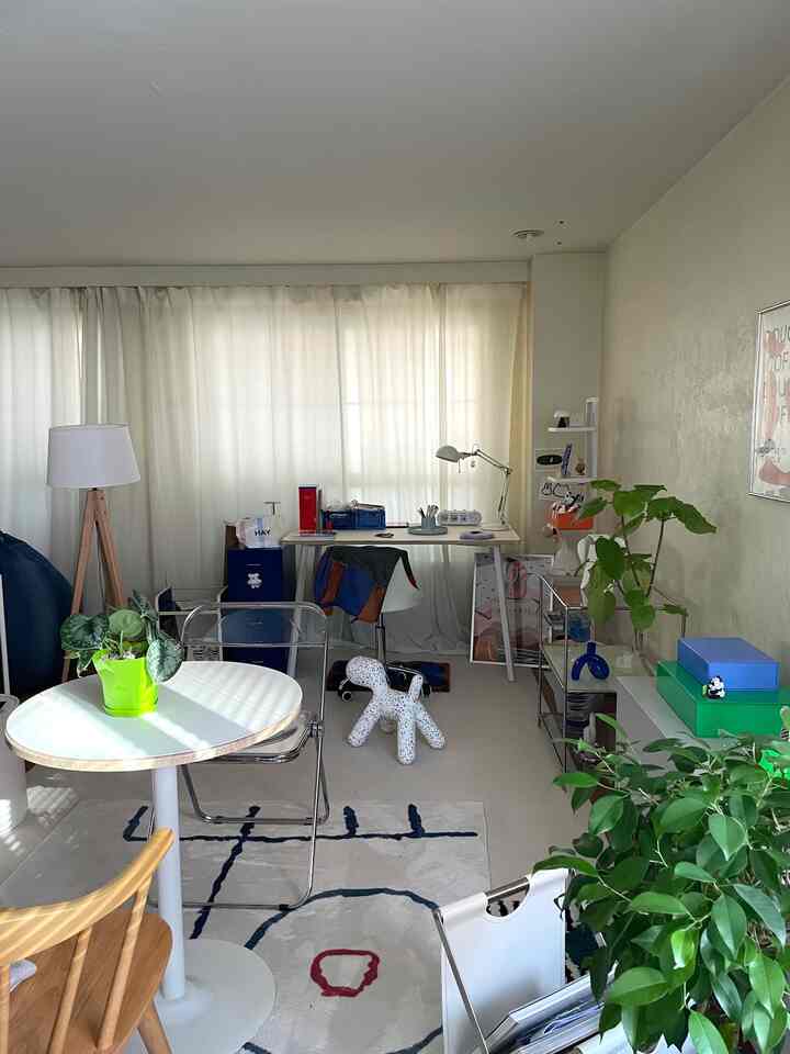 白と緑のトーンが特徴的なコンパクトなホームオフィス、植物とミッドセンチュリーモダン家具が配置された雰囲気のあるインテリア