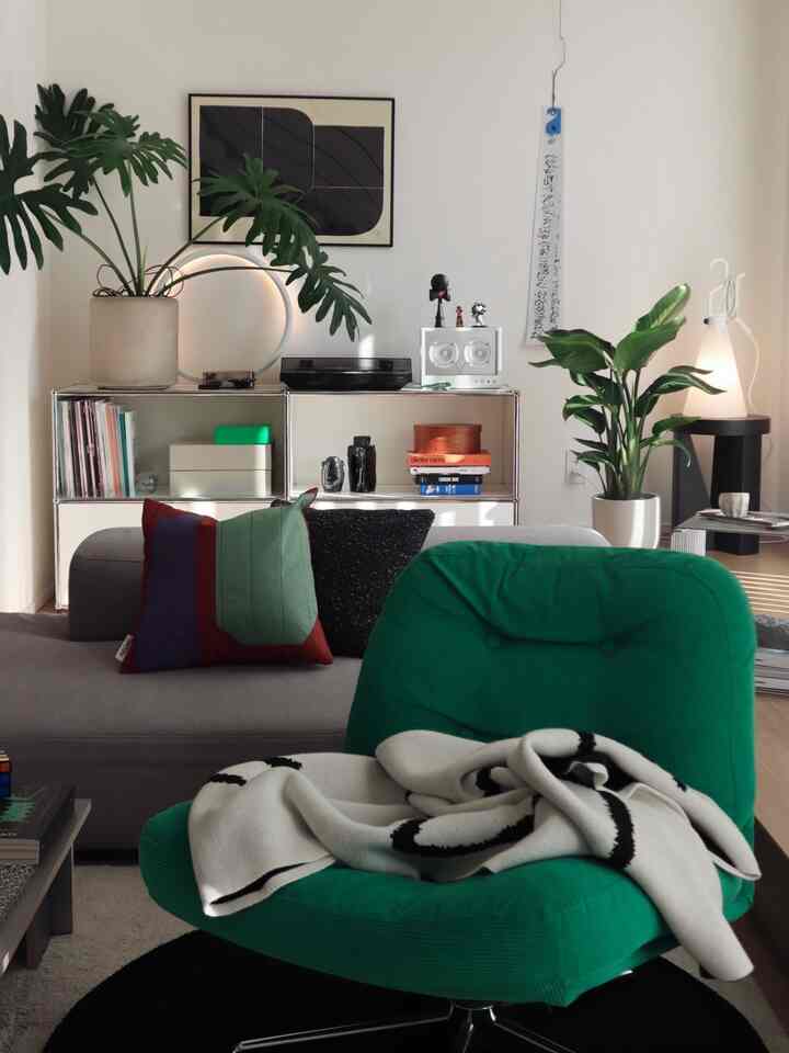 ホワイトとグレーを基調に、グリーンのアームチェアと植物が配置されたモダンなリビング