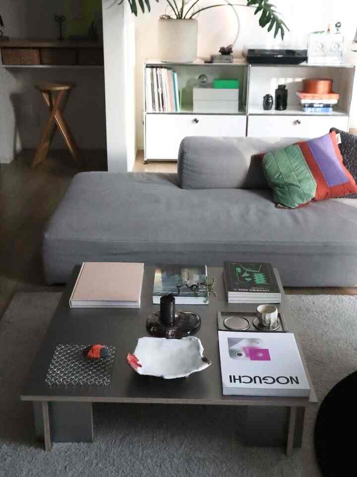 ナチュラルな色調のリビングルーム、グレーのソファとシルバーのコーヒーテーブルが配置された快適な空間