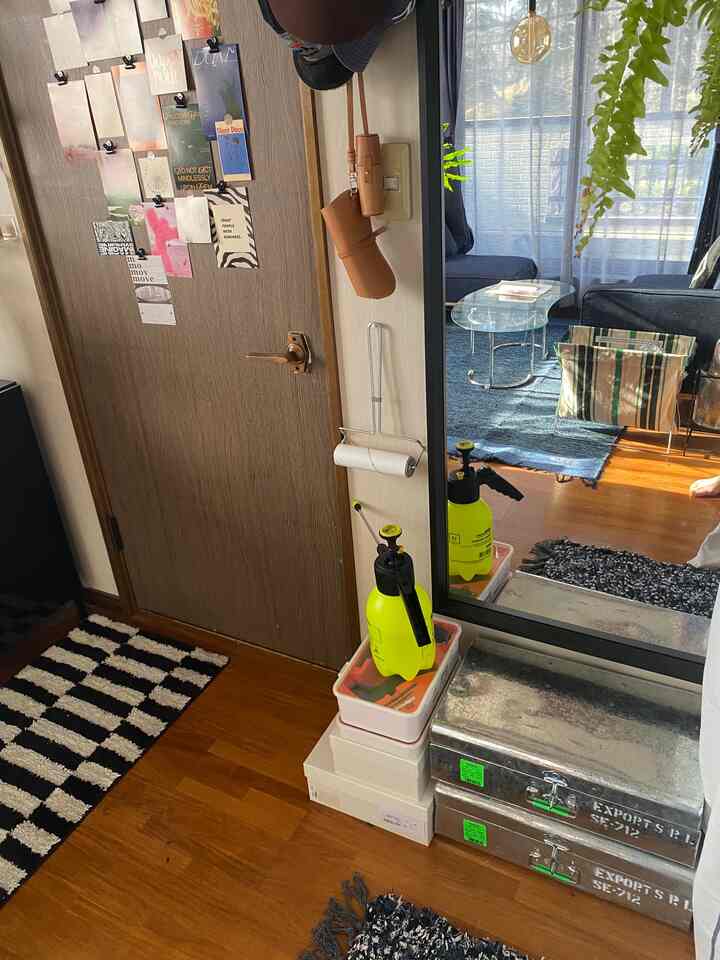 木目調と白い壁の玄関、コーナーと床に収納トランクと整理ボックスが配置された清潔感のある空間