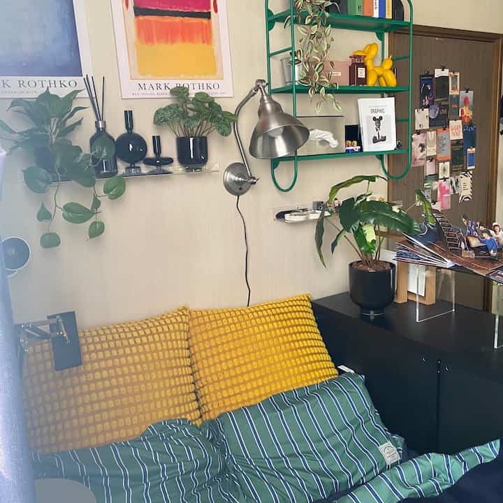 黄色と緑の色調のリビング、ソファとクッション、植物が配置された温かみのある室内