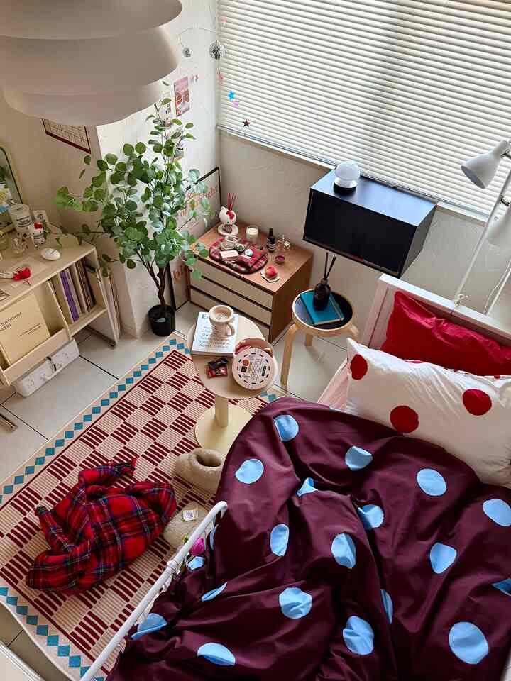 Cozy studio bedroom with natural wood tones, red accents, and blue polka dot bedding