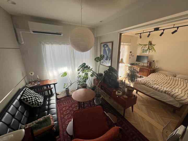 ナチュラルな木目調と白いカーテンが調和する1LDKのリビングと寝室空間、モダンヴィンテージスタイルの植物と家具が印象的な落ち着いた雰囲気のインテリア