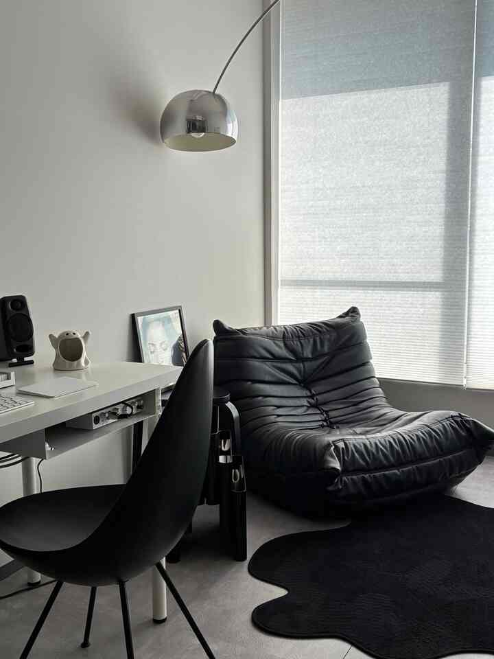モノトーンの黒を基調としたホームオフィス空間、黒いソファと椅子、クロームの照明、グレーのブラインドが配置されたモダンな雰囲気