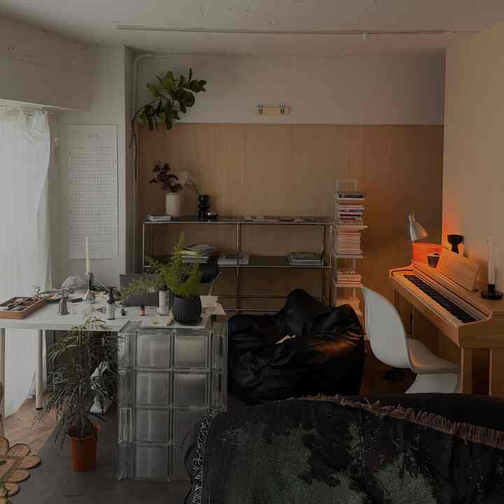 ナチュラルカラーと黒を基調とした趣味兼作業スペース、ピアノとデスク、ビーンバッグチェアが配置された雰囲気のあるインテリア