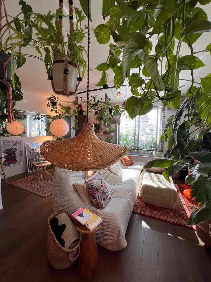 緑豊かな植物が囲む明るく居心地の良いリビング、ナチュラルな木目調と白いソファを配置したインテリア