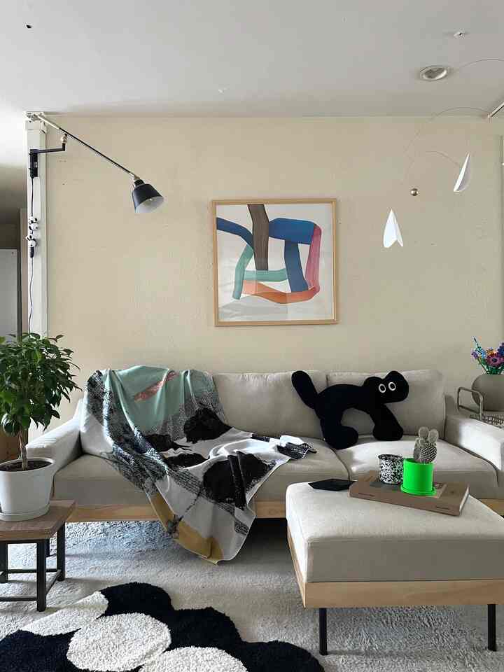 Beige-toned living room featuring a mid-century modern sofa with a cat-shaped cushion, creating a cozy atmosphere