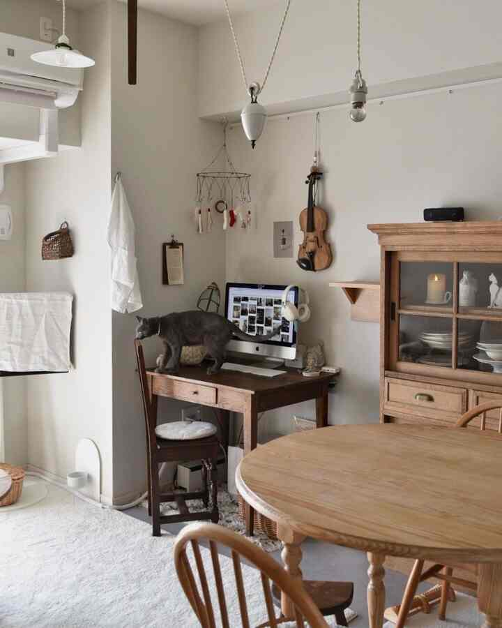 ナチュラルな色調のホームオフィス、木製のダイニングテーブルとデスク、机の上を歩く猫がいる雰囲気のあるインテリア