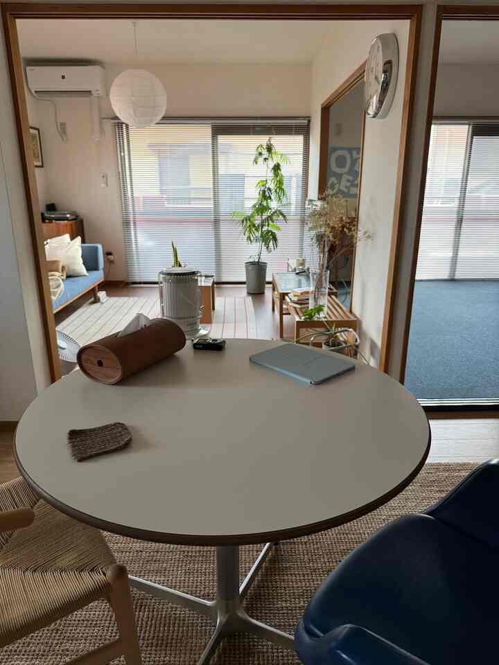 ナチュラルカラーと木目調のダイニングルーム、丸いダイニングテーブルとブラインドが配置された雰囲気のある空間