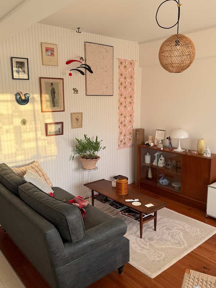 温かみのある木目調とヴィンテージソファ、植物、ペンダントライトが配置された居心地の良いリビング