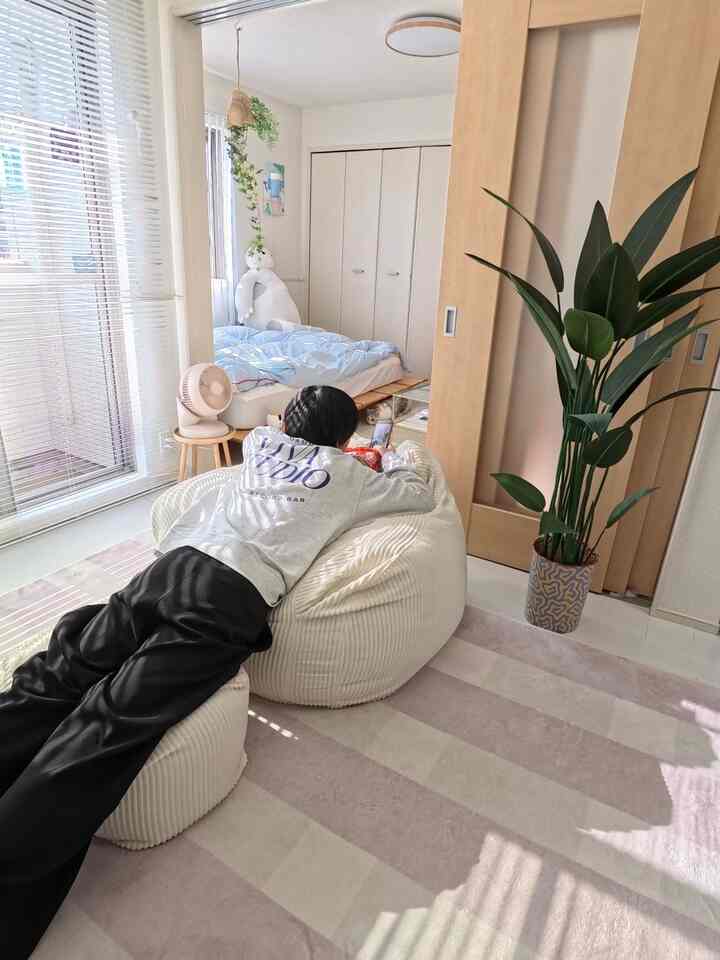 白とベージュの色調の1LDK、中央に大きなビーズクッションとベージュのラグが配置された自然で落ち着いた印象の空間