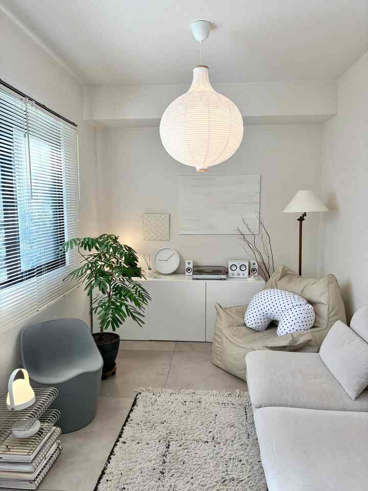 白とベージュの落ち着いたリビング、ソファとビーズクッション、観葉植物とペンダントライトが配置された雰囲気のあるインテリア