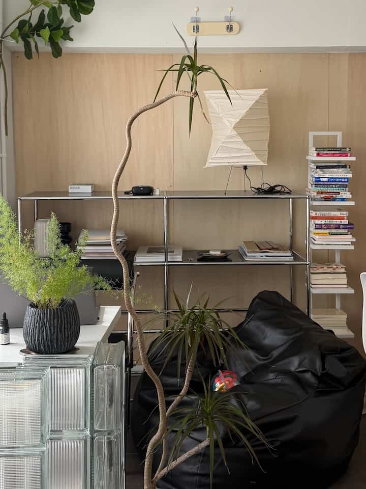 ナチュラルな木目調の壁にシンプルでモダンな家具が配置されたホームオフィス空間、黒いビーズクッションと白いフロアランプがアクセントとなっているインテリア