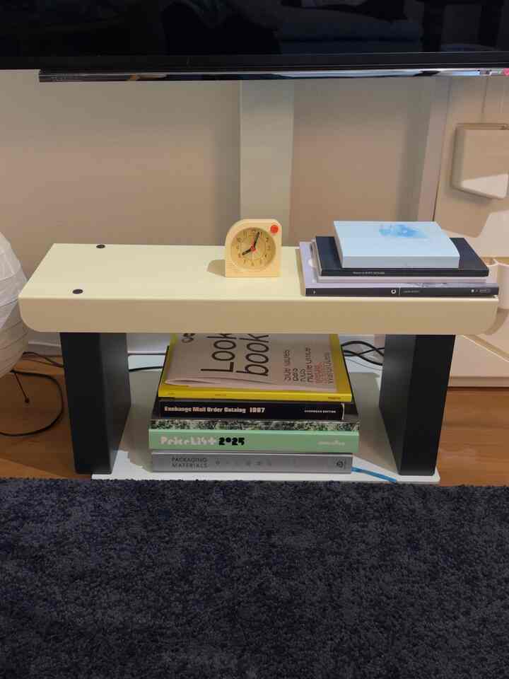 白と黒のミニベンチ、時計と積み重ねられた本が配された落ち着いた一人暮らしの空間