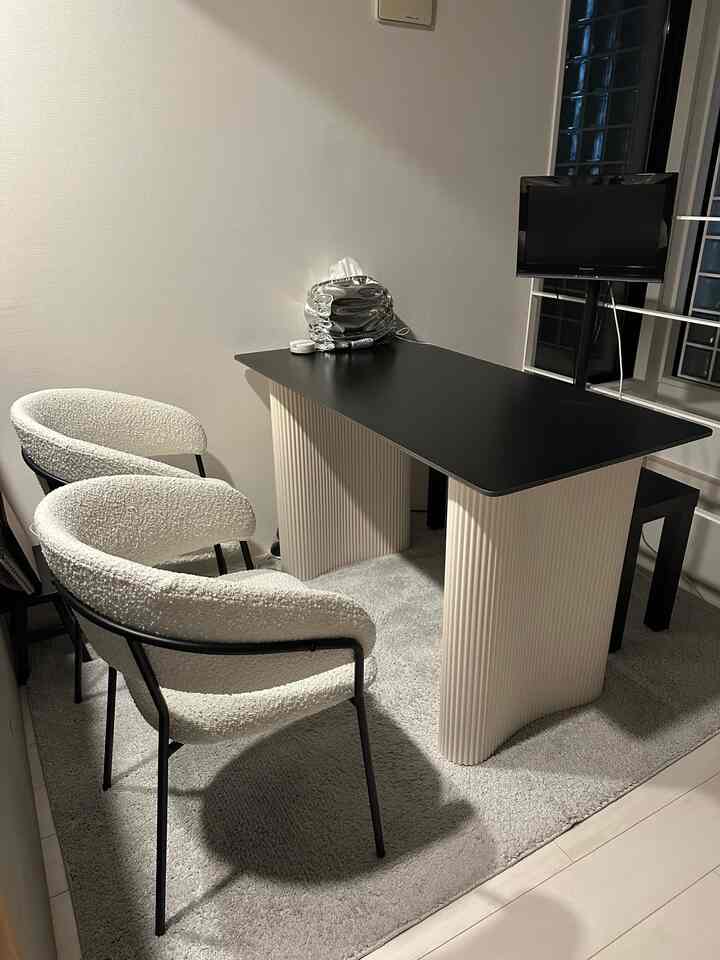 ベージュと黒の色調のリビング、モダンなダイニングテーブルと椅子が配置されたシンプルで落ち着いた印象的な空間