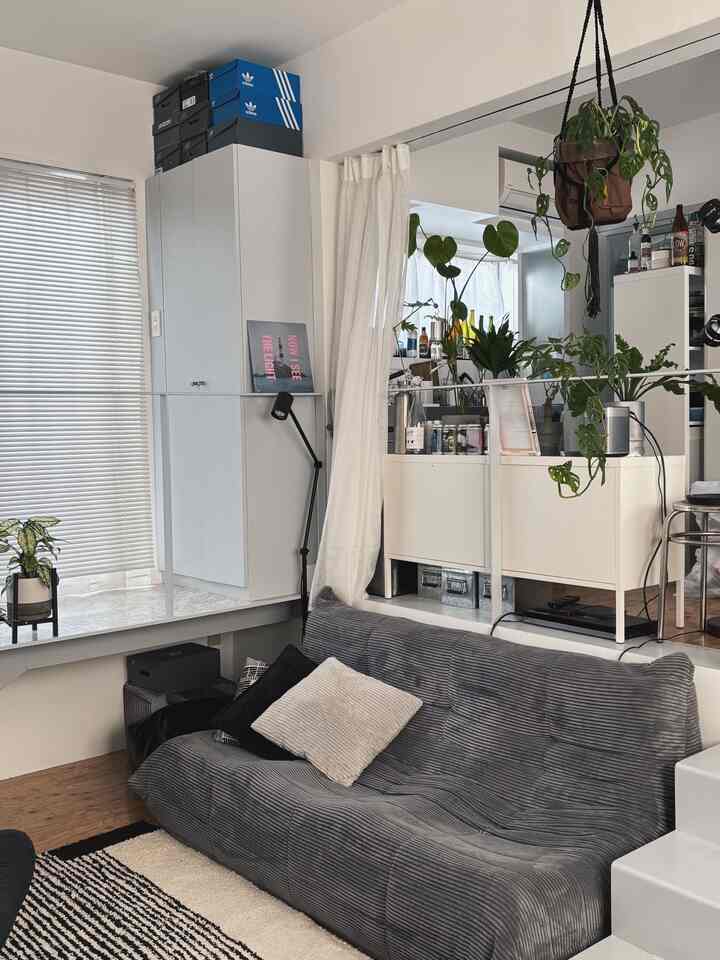 White and gray tone living room featuring a gray corduroy sofa and white cabinets with a natural modern feel