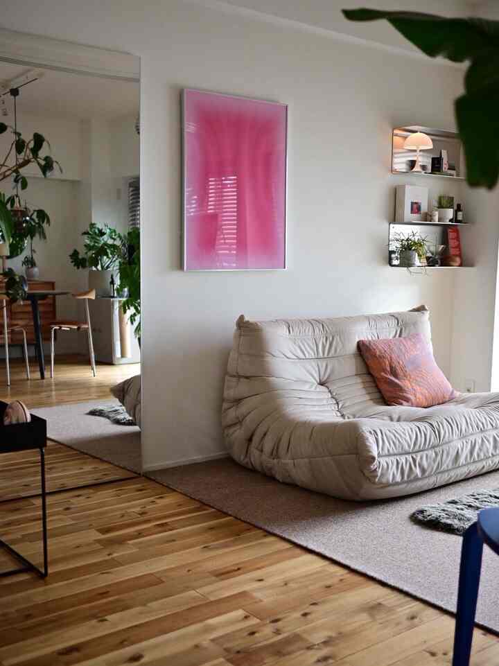 Natural toned living room featuring a beige sofa and pink poster, creating a cozy atmosphere
