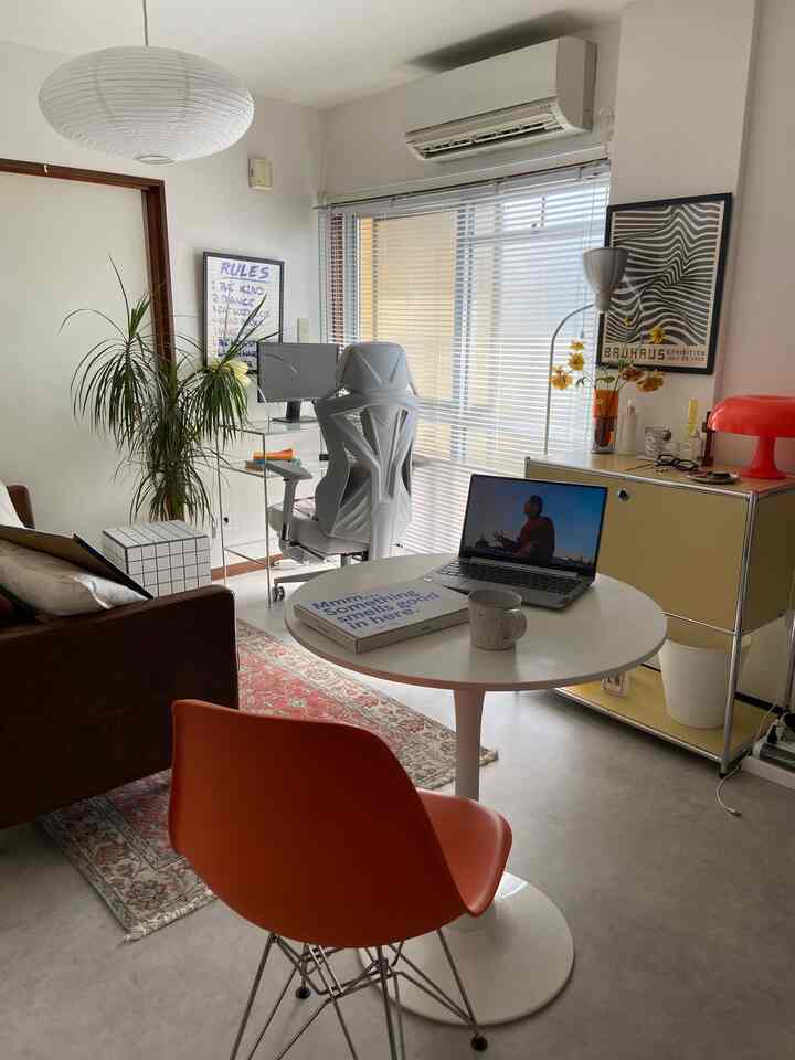 White and orange-toned single household living room featuring a home office for remote work with mid-century modern furniture in a tidy space