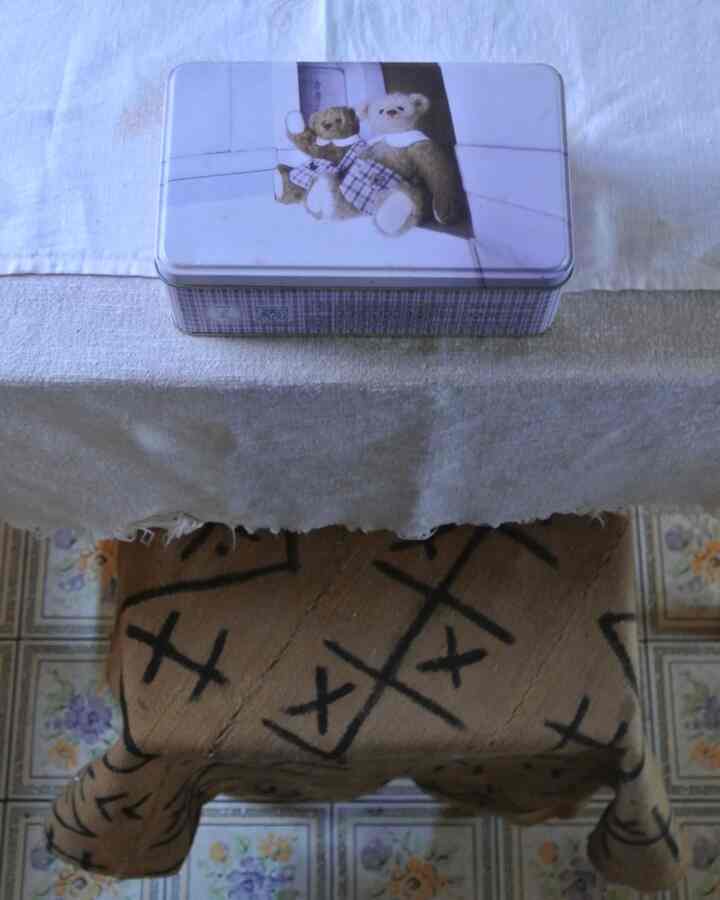 ブラウンとホワイトのトーンが調和するダイニングテーブルの上に、ヴィンテージ風のクマの絵が描かれた金属製の箱が置かれた温かみのある空間