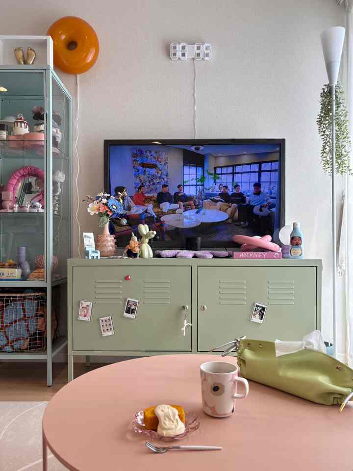 ホワイトとミントの色調が調和したリビング、ミントのキャビネットとピンクのコーヒーテーブルが配置された雰囲気のあるインテリア