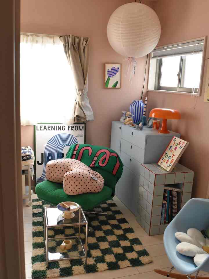 Compact room with pink-toned walls, green armchair, and glass side table creating an open yet cozy atmosphere