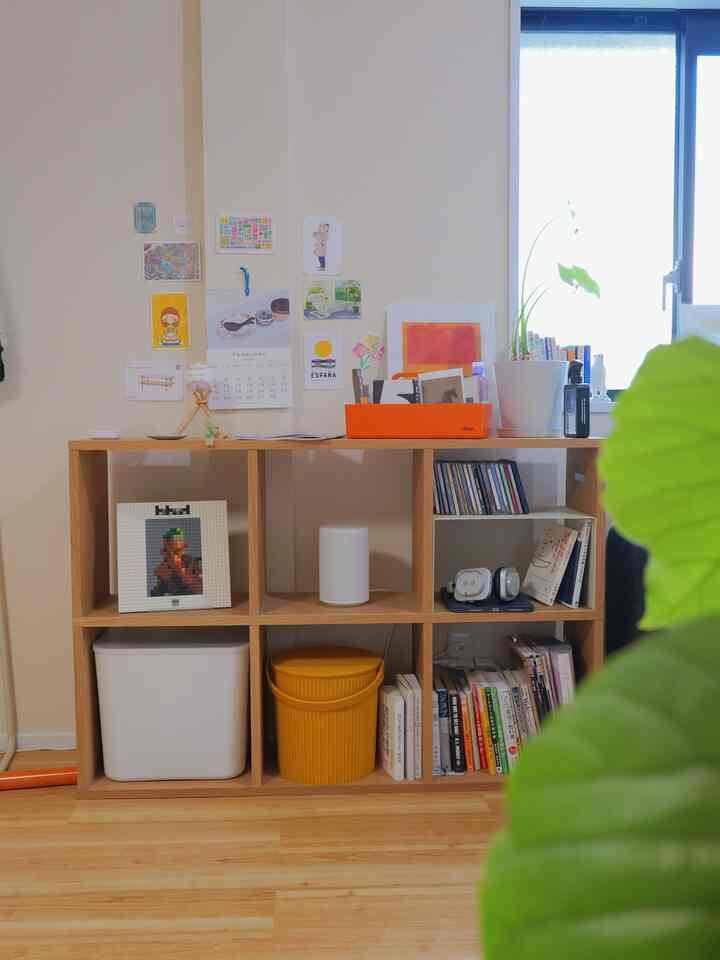 Natural wood tone and beige wall space featuring a shelf with books and accessories in a tidy interior